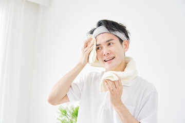 家でタオルで顔を拭く男性