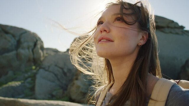 Woman, windy beach and looking at sky, weather or thinking while on travel, holiday or summer trip. Girl, outdoor and sunshine by ocean, sea or sand for freedom, vacation oe relax in nature with view
