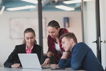 Successful young female leader in a suit with a pink shirt sitting in a modern glass office with a determined smile.