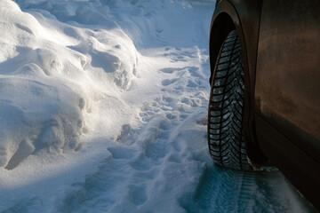 Closeup of car wheel on a snowy road at winter. Dangerous driving conditions.