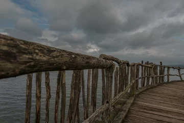 Papier Peint photo Lavable Ville sur leau Long wooden pier with fence by Lake Constance with gray cloudy sky, Germany