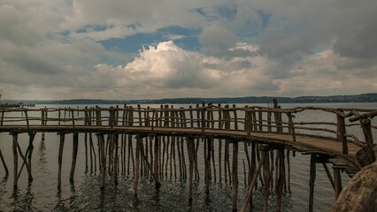 Beautiful view of wooden pier with fence by Lake Constance with gray cloudy sky, Germany