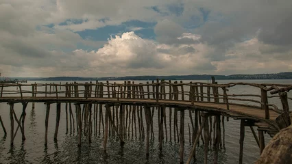 Papier peint photo autocollant rond Ville sur leau Beautiful view of wooden pier with fence by Lake Constance with gray cloudy sky, Germany