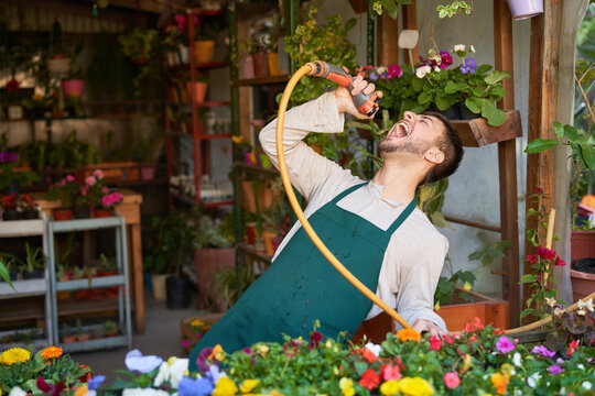 Florist in flower shop has fun singing with garden hose