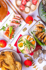 Traditional Chinese lunar New Year dinner table, party invitation, menu background with pork, fried fish, chicken, rice balls, dumplings, fortune cookie, nian gao cake, noodles, chinese decorations