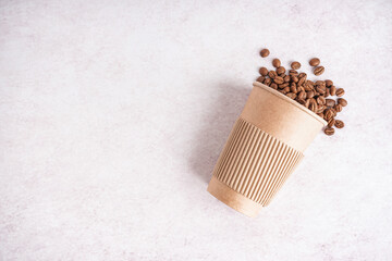 Paper cup with coffee beans on light background