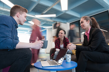 Multiethnic startup business team on meeting in a modern bright open space coworking office. Brainstorming, working on laptop. Group of coworkers walking around in motion blur.