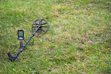 Metal detector laying outdoors on the grass. Close up electronic treasure finder.