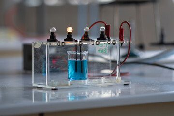 Electrolyte solution turns on a light bulb. Experiment in the chemistry laboratory