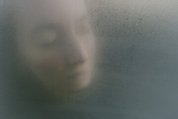 Woman dreamy or mystery portrait through the glass. Psychological concept of concentrating