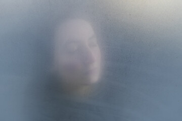 Woman dreamy or mystery portrait through the glass. Psychological concept of concentrating