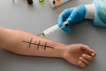Doctor with syringe making allergy skin test on patient's hand in clinic, closeup