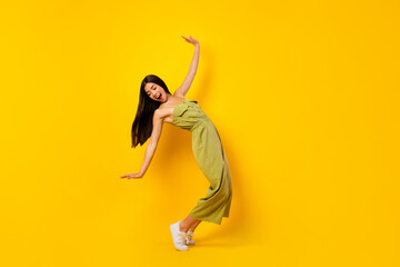Full body portrait of satisfied glad malaysian lady standing tiptoe dance isolated on yellow color background