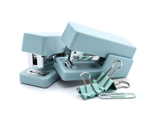 Office staplers and paper clips on white background