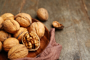 Plate of fresh walnuts on wooden table, closeup