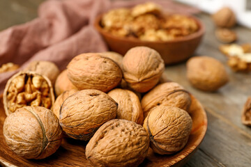 Plate of fresh walnuts on wooden table, closeup