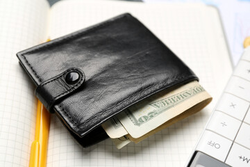 Wallet with money and pen on notebook, closeup. Budget concept