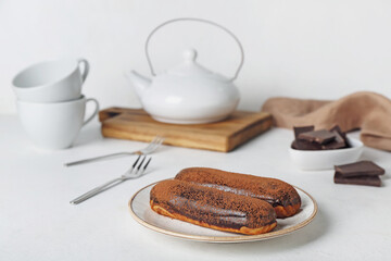 Plate with delicious chocolate eclairs on light table