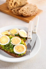 Plate of tasty toasts with boiled egg on light table, closeup