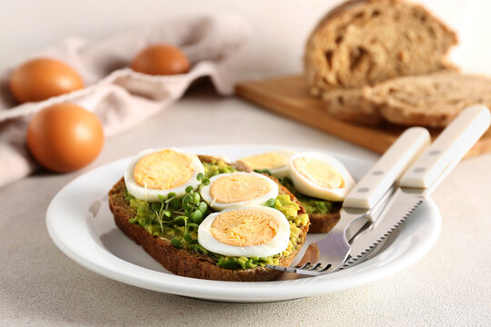 Plate of tasty toasts with boiled egg on light table, closeup