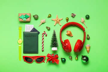 Travel accessories with Christmas decor, gifts and seashells on green background
