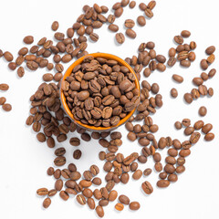 Scattered coffee beans on a white photo and a mug with coffee beans.