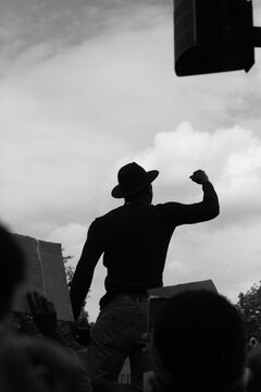 Grayscale of a male in hat fighting for human rights