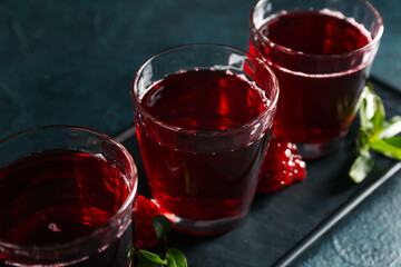 Board with glasses of fresh pomegranate juice on dark color background, closeup