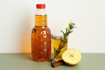 Bottle and glass of fresh apple juice with rosemary on color table