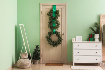 Interior of hall with wooden door, Christmas wreaths and mirror