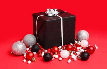 Stylish Christmas gift box and balls on red background
