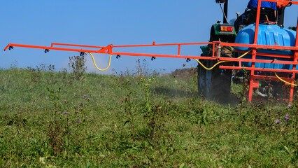 A tractor with a tank and attached equipment for spraying the field from pests and weeds, the process of processing the field.