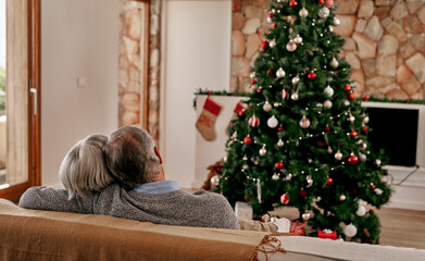 Senior couple, christmas and hug from back view relax on sofa in living room with christmas tree....