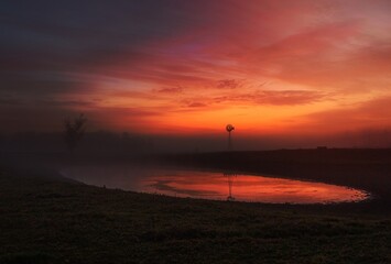 Red skies at dawn with light mist across rural farmlands