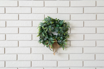 Christmas mistletoe wreath hanging on white brick wall