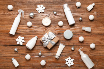 Cosmetic products with Christmas decor and gift on wooden background
