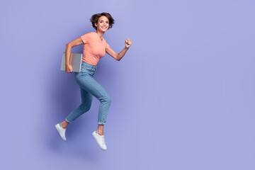 Fototapeta na wymiar Full length photo of cute shiny lady wear striped t-shirt jumping high running holding modern device empty space isolated violet color background
