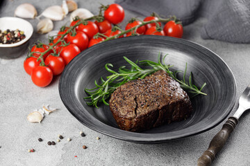 Medium rare roast beef with  juicy red tomatoes in a black plate on a stone table