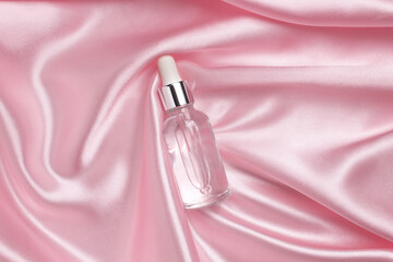 A face serum or natural essential oil lying on a pink fabric