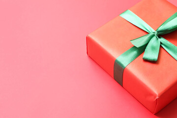 Christmas gift box with green bow on red background, closeup