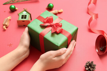 Woman with gift and Christmas decor on red background, closeup