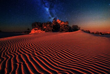 Sand dunes under starry night sky