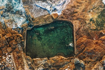 Fototapeta premium Swimmers refresh themselves in coastal rock pool early morning.