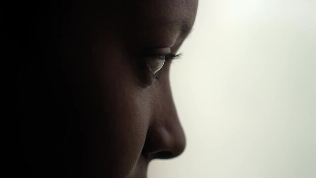 Close up of an African american woman's eyes working using a computer to work. Freelancer female gaze looking at laptop, eye reflected by screen light.
