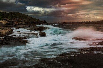 Wave action on coastal rocks with waterfall cascades