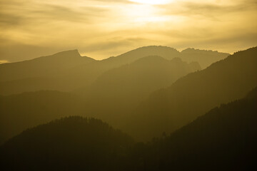 Spectacular view of mountain ranges silhouettes with yellow sunlight. Sunset in Allgau, Germany, Alps.