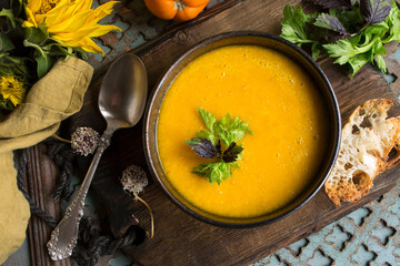 bowl with traditional spanish yellow tomato gazpacho soup on wooden table