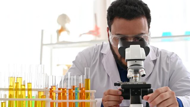 4K Scientist looking through a microscope in laboratory