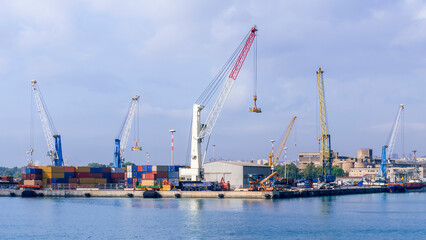 Fototapeta na wymiar cargo sea port with cranes, container stacks and trucks with goods, sea hub terminal from seashore