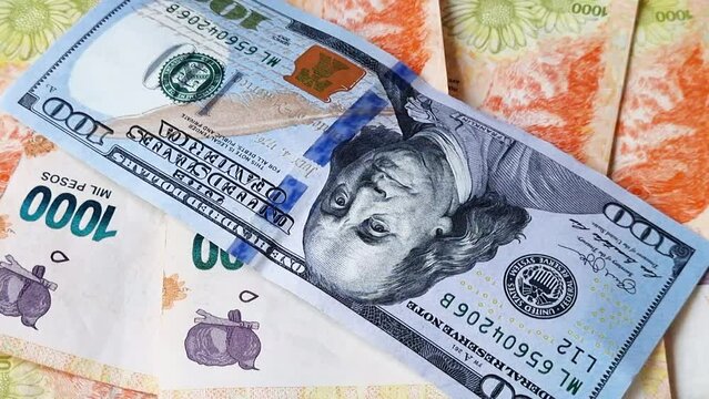 Hundred dollar bill over an amount of devalued Argentine pesos.